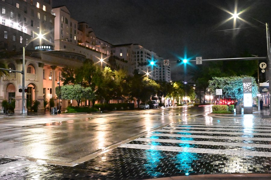 Traffic lights cast green reflections across an intersection