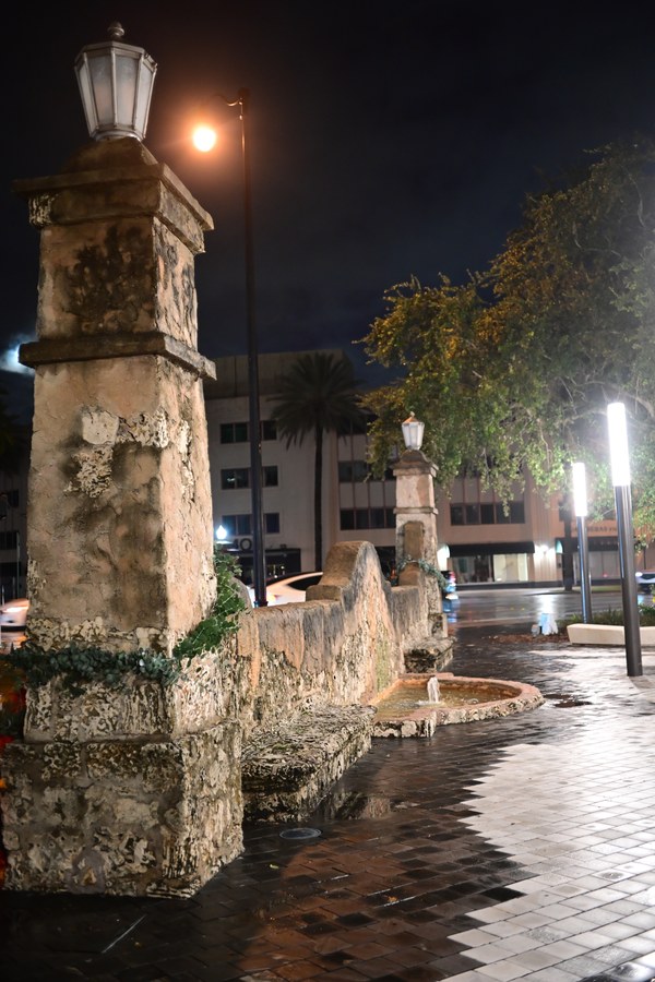 A stone fountain and a lamp in the night